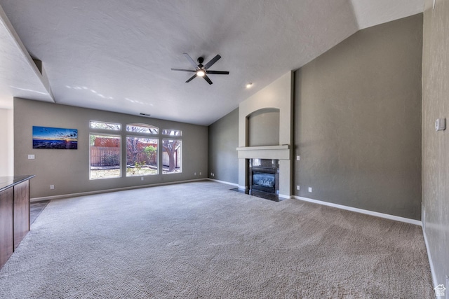 unfurnished living room featuring a fireplace with flush hearth, carpet flooring, a ceiling fan, and lofted ceiling