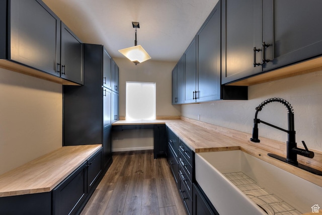 kitchen with a sink, butcher block countertops, pendant lighting, and dark wood-style flooring