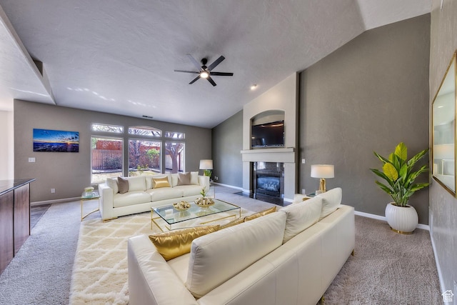 carpeted living room featuring baseboards, a ceiling fan, a textured ceiling, a fireplace with flush hearth, and lofted ceiling