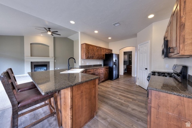 kitchen with a peninsula, a ceiling fan, appliances with stainless steel finishes, arched walkways, and a sink