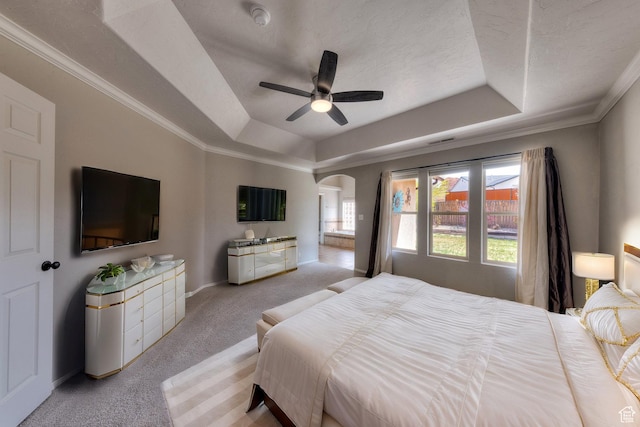 bedroom featuring arched walkways, a textured ceiling, crown molding, a tray ceiling, and light carpet