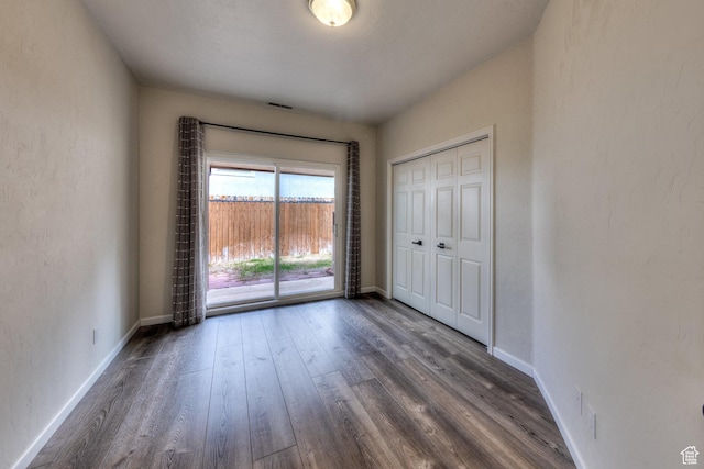 unfurnished bedroom with access to outside, dark wood-style flooring, and baseboards