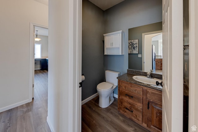 bathroom featuring toilet, wood finished floors, vanity, and baseboards