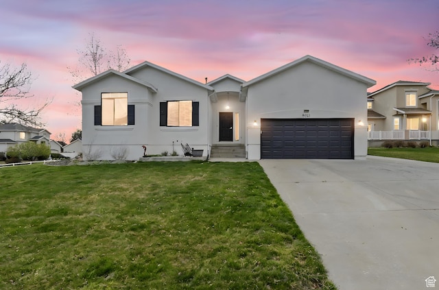 ranch-style house with a garage, driveway, stucco siding, and a front lawn
