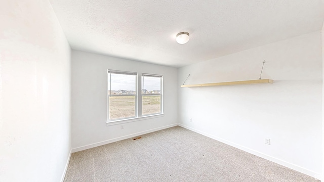 carpeted empty room featuring visible vents, a textured ceiling, and baseboards