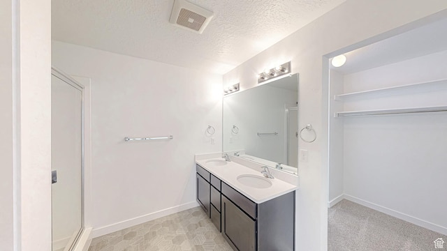 bathroom featuring a sink, visible vents, a shower stall, and a textured ceiling