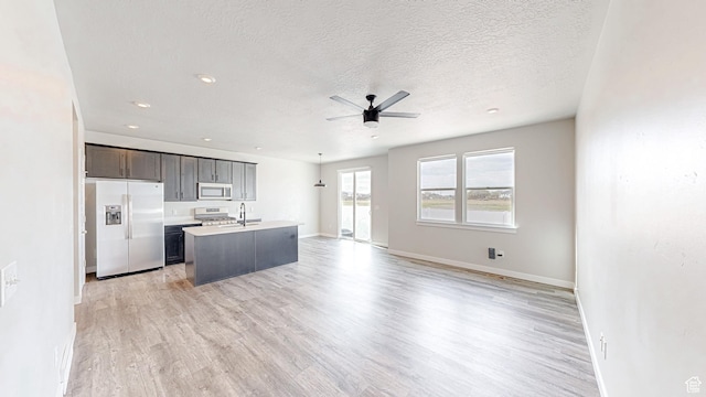 kitchen featuring stainless steel microwave, fridge with ice dispenser, open floor plan, and gas range oven