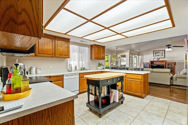 kitchen with a peninsula, brown cabinets, dishwasher, and light tile patterned floors