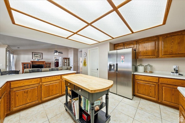 kitchen with stainless steel refrigerator with ice dispenser, brown cabinets, light countertops, and light tile patterned flooring