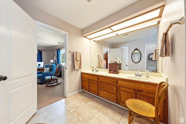 full bath featuring tile patterned floors, double vanity, baseboards, and a sink