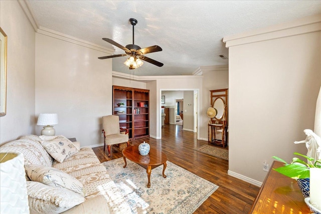 living room with baseboards, a textured ceiling, crown molding, ceiling fan, and wood finished floors