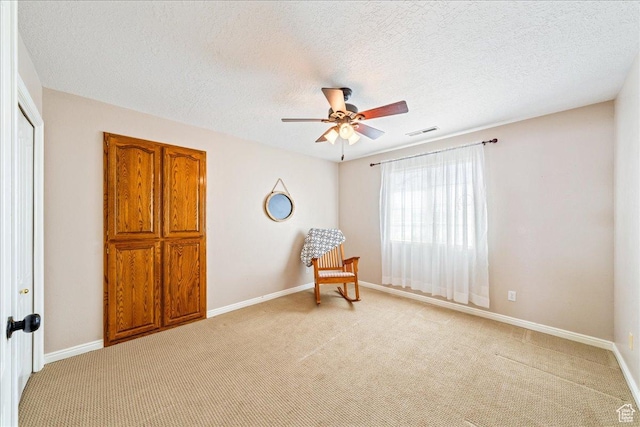 sitting room with visible vents, a ceiling fan, and light colored carpet