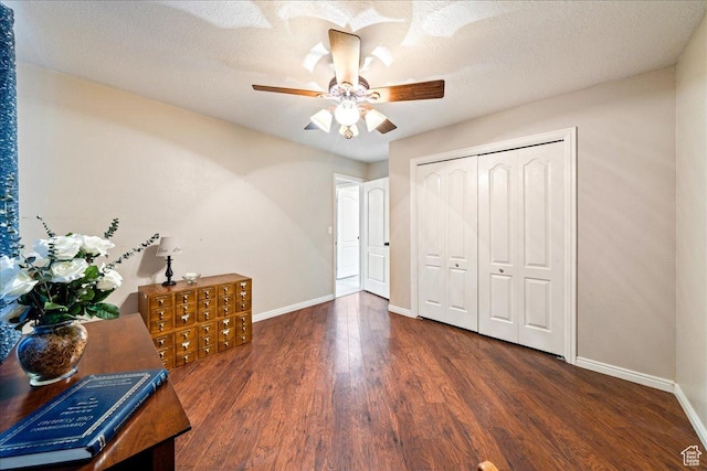 interior space with a textured ceiling, a closet, a ceiling fan, wood finished floors, and baseboards
