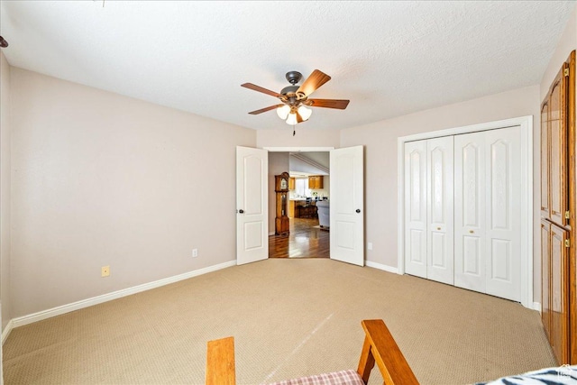 unfurnished bedroom featuring a closet, baseboards, light carpet, and a textured ceiling