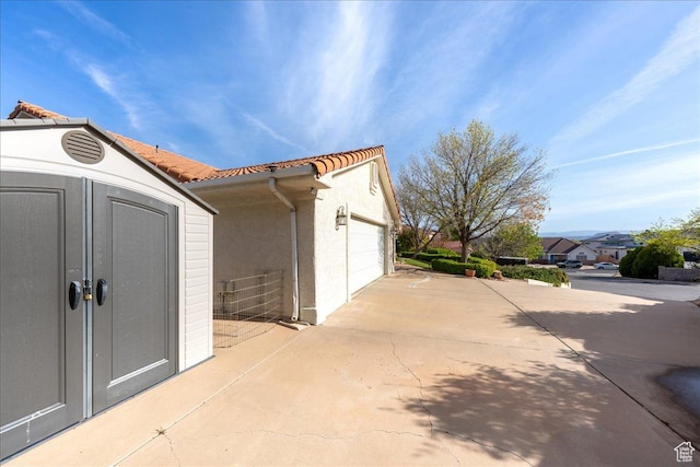 exterior space featuring a tile roof, stucco siding, and an outdoor structure
