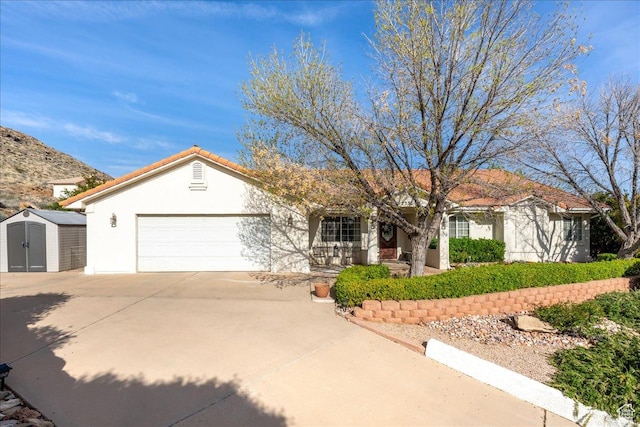 ranch-style home featuring a storage shed, covered porch, a garage, concrete driveway, and stucco siding