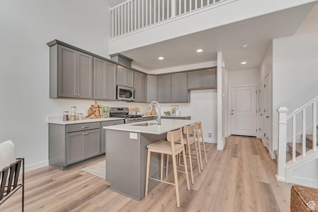 6864 S Static Peak Dr Unit 258, West Jordan, UT 84081 - kitchen with a breakfast bar, a sink, stainless steel appliances, light wood-type flooring, and gray cabinets