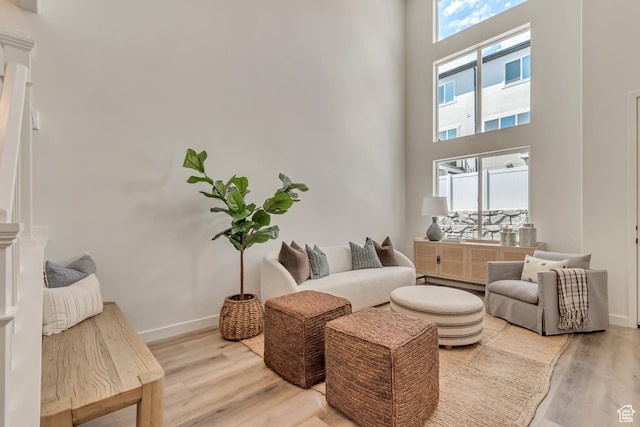 6864 S Static Peak Dr Unit 258, West Jordan, UT 84081 - living area with light wood-style flooring, baseboards, and a towering ceiling