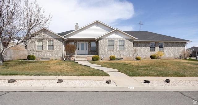 view of front of house with a chimney, a front yard, and brick siding