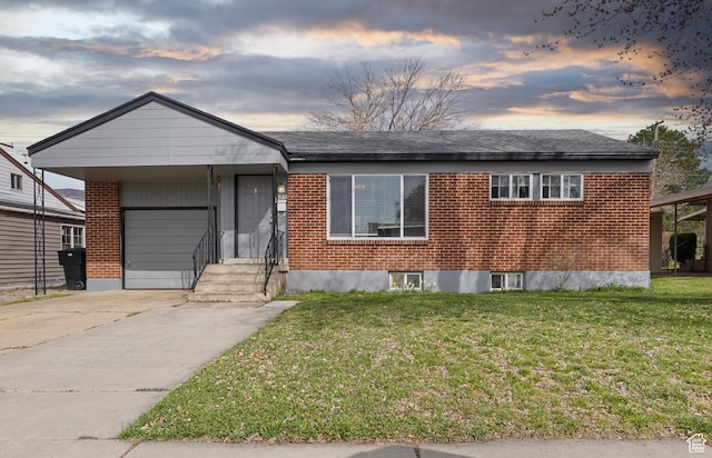 single story home with concrete driveway, a yard, brick siding, and an attached garage