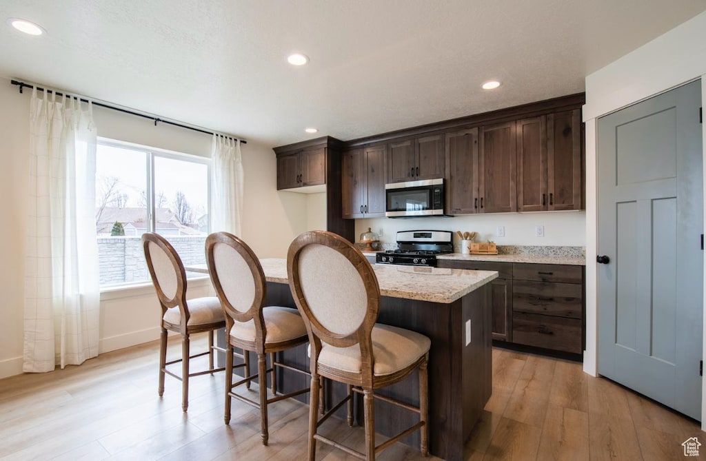 857 S 1300 E, Spanish Fork, UT 84660 - kitchen with appliances with stainless steel finishes, light wood-style floors, dark brown cabinetry, recessed lighting, and a breakfast bar area