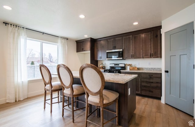 857 S 1300 E, Spanish Fork, UT 84660 - kitchen with appliances with stainless steel finishes, light wood-style floors, dark brown cabinetry, recessed lighting, and a breakfast bar area