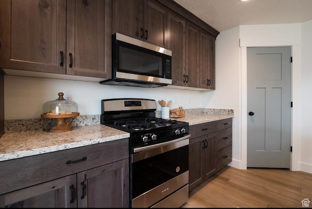 857 S 1300 E, Spanish Fork, UT 84660 - kitchen with light wood-type flooring, appliances with stainless steel finishes, dark brown cabinets, and light stone counters
