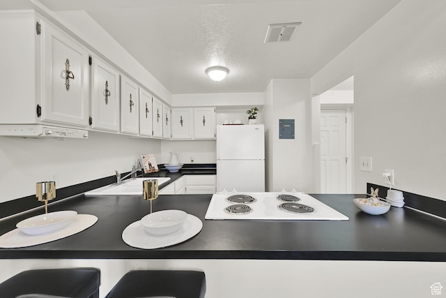 1298 Lorl Ln Unit 2, Ogden, UT 84404 - kitchen with a peninsula, freestanding refrigerator, dark countertops, white cabinets, and stovetop