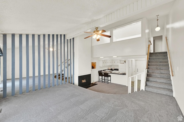 1298 Lorl Ln Unit 2, Ogden, UT 84404 - living area with ceiling fan, a fireplace with flush hearth, a textured ceiling, carpet floors, and stairs