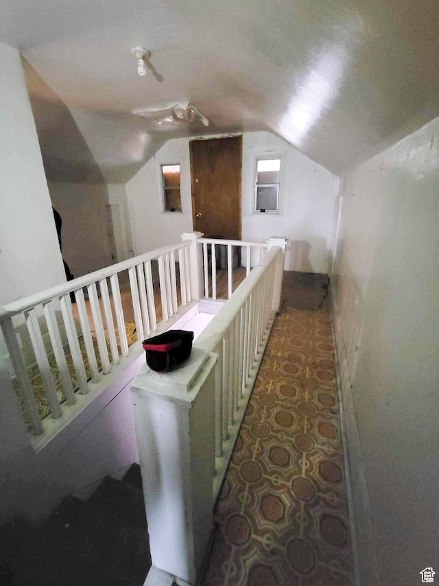 corridor featuring an upstairs landing and lofted ceiling