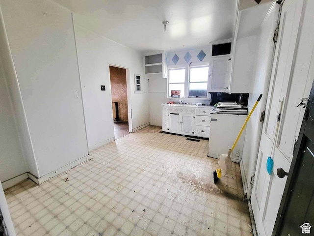 kitchen with baseboards, light countertops, white cabinets, and light floors