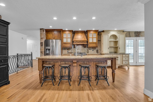 307 E 680 N, Lindon, UT 84042 - kitchen with custom exhaust hood, glass insert cabinets, backsplash, stainless steel refrigerator with ice dispenser, and light wood-style floors