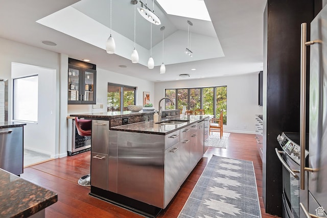 579 E 13th Ave, Salt Lake City, UT 84103 - kitchen with glass insert cabinets, a sink, dark wood-style flooring, a center island with sink, and stainless steel appliances