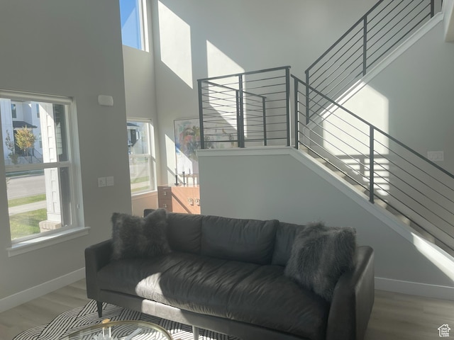 living area featuring wood finished floors, baseboards, stairway, and a towering ceiling