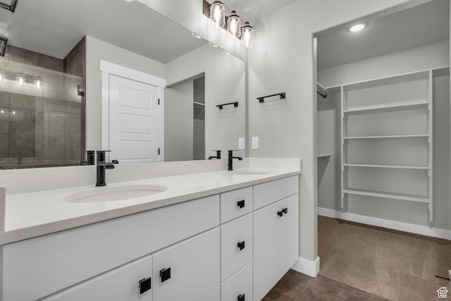 full bath with a sink, a spacious closet, a shower stall, and double vanity
