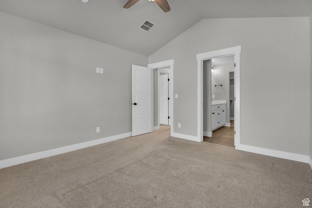 unfurnished bedroom featuring baseboards, ensuite bath, visible vents, lofted ceiling, and light colored carpet