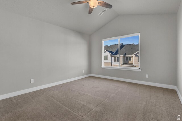 carpeted spare room featuring visible vents, baseboards, a ceiling fan, and lofted ceiling