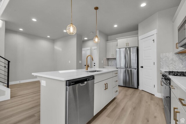 kitchen featuring a sink, light countertops, light wood-type flooring, an island with sink, and stainless steel appliances