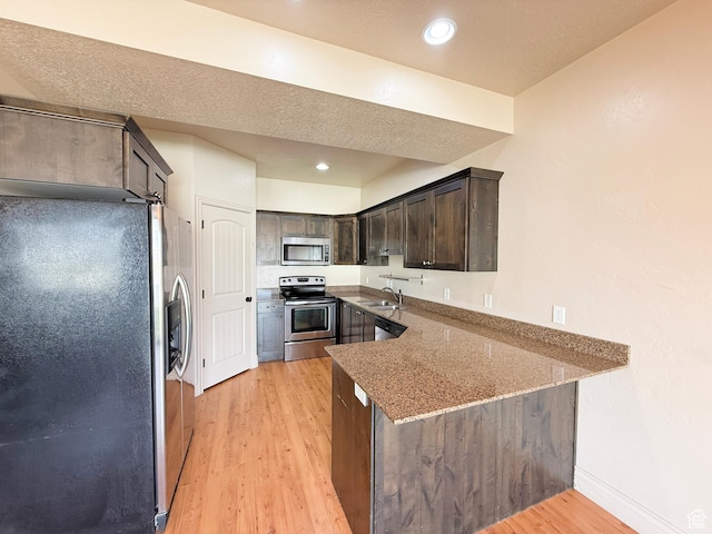141 E 620 S, Smithfield, UT 84335 - kitchen with dark brown cabinetry, light wood-style flooring, a peninsula, light stone counters, and stainless steel appliances