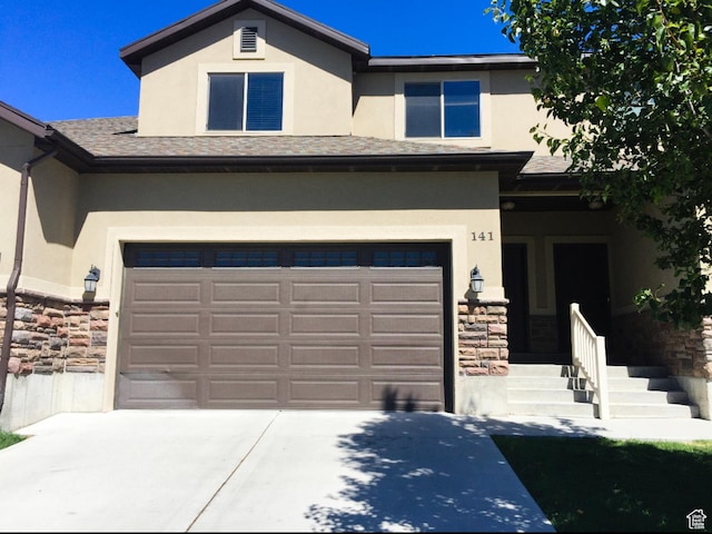 view of front of home featuring concrete driveway, stone siding, a garage, and stucco siding