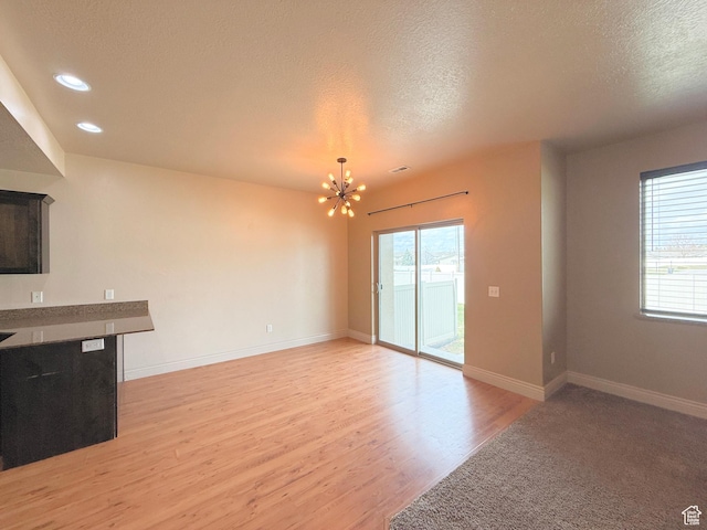 141 E 620 S, Smithfield, UT 84335 - unfurnished living room with light wood-style floors, a notable chandelier, a textured ceiling, and a wealth of natural light