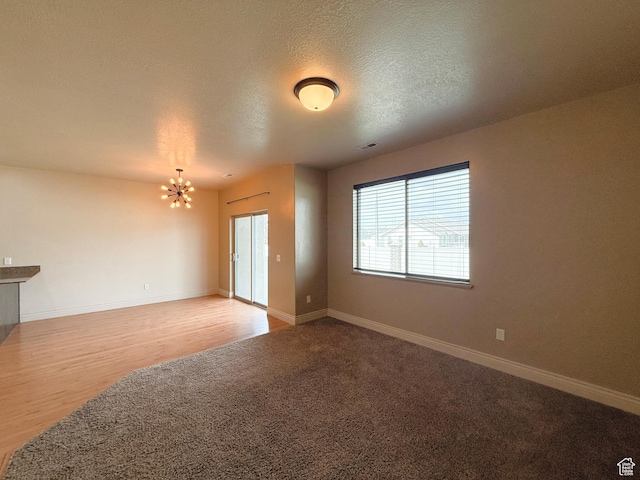 141 E 620 S, Smithfield, UT 84335 - empty room featuring baseboards, an inviting chandelier, a textured ceiling, visible vents, and wood finished floors