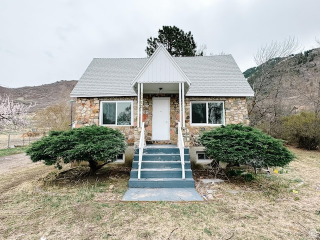 view of front of property featuring roof with shingles and stone siding