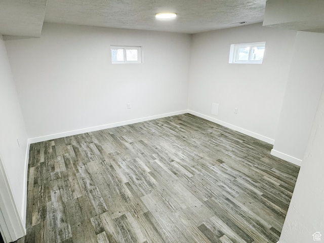 below grade area featuring a textured ceiling, wood finished floors, and baseboards