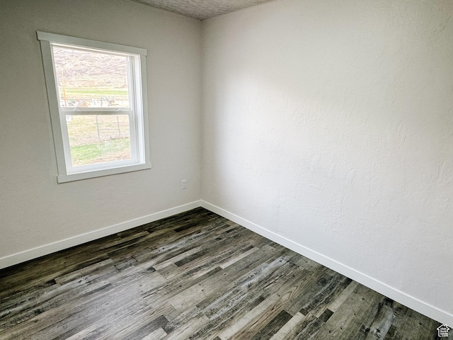 empty room featuring baseboards and dark wood-style floors