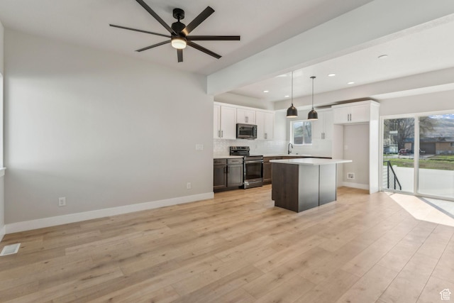 kitchen with a ceiling fan, a center island, a sink, stainless steel appliances, and light wood finished floors