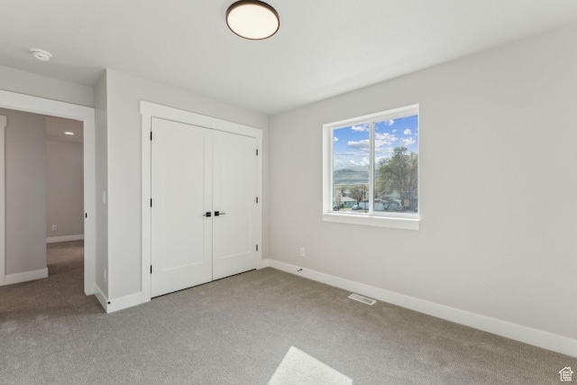 unfurnished bedroom with a closet, carpet flooring, visible vents, and baseboards