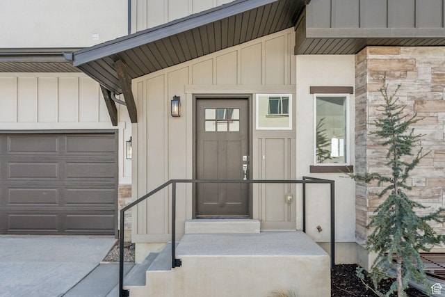 entrance to property with board and batten siding, an attached garage, and stone siding
