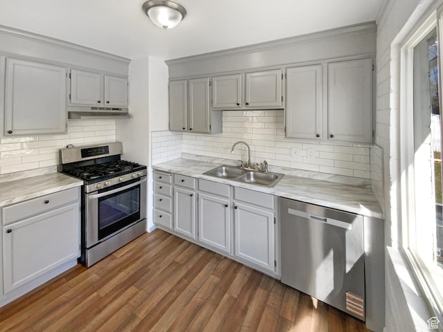 kitchen featuring a sink, light countertops, appliances with stainless steel finishes, under cabinet range hood, and wood finished floors