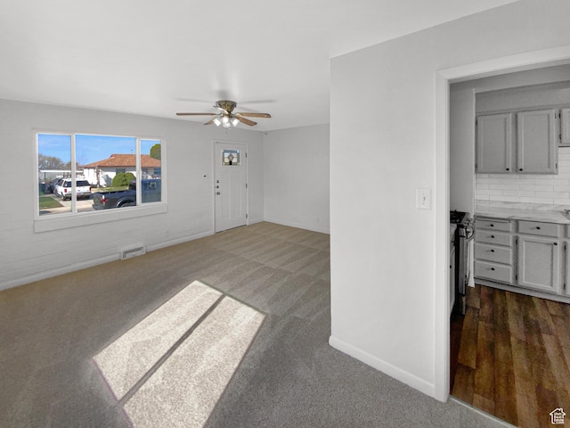 unfurnished living room featuring carpet flooring, baseboards, a ceiling fan, and visible vents